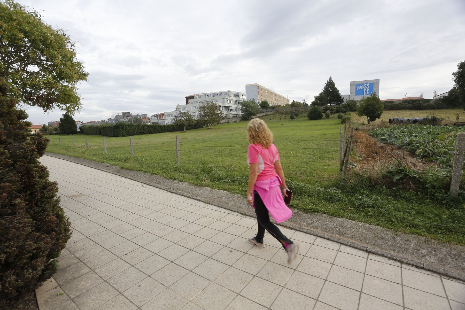 Una mujer pasea por delante de la finca donde se construirá el nuevo conservatorio en Torrelavega.