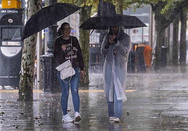 Dos jóvenes se cubren bajo uno de los intensos chaparrones.