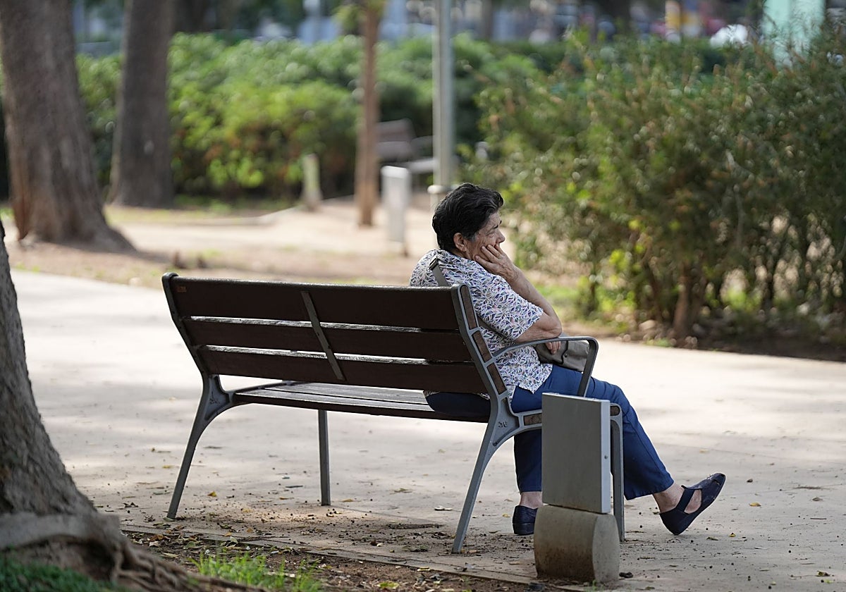 Una mujer jubilada sentada en un banco.