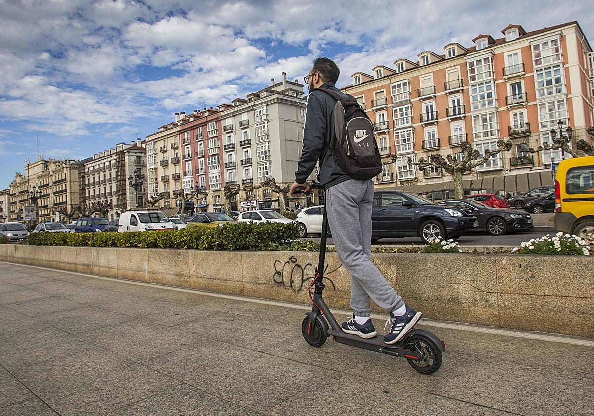 Un hombre conduce su patinete eléctrico por la acera en el centro de Santander.