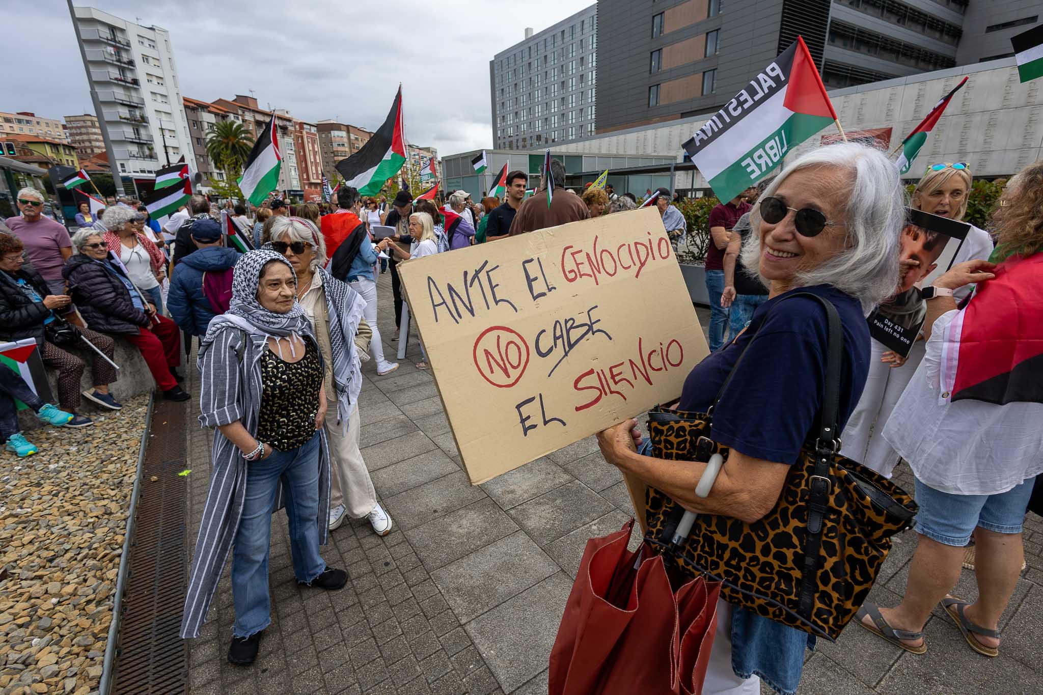 Una señora porta un cartel en el que se puede leer: 'Ante el genocidio, no cabe el silencio'. 