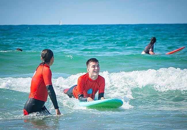 Uno de los chicos disfruta encima de la tabla en la playa de Somo.