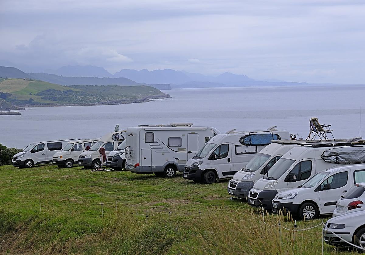 Varios vehículos, entre ellos autocaravanas, estacionados en una finca particular del parque natural de Oyambre.