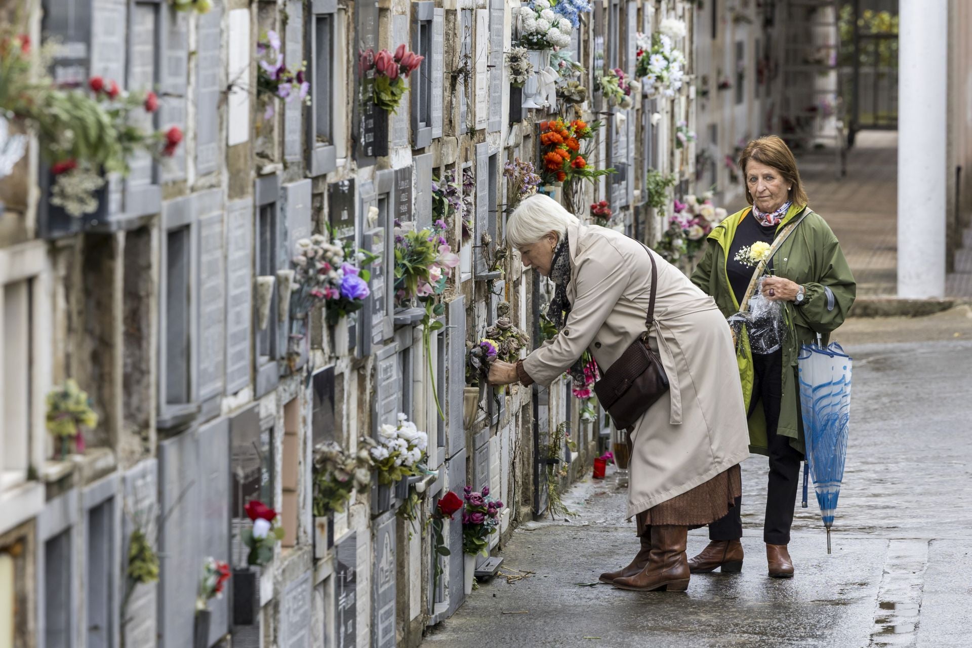 Dos mujeres ponen flores en un nicho este sábado en Ciriego.