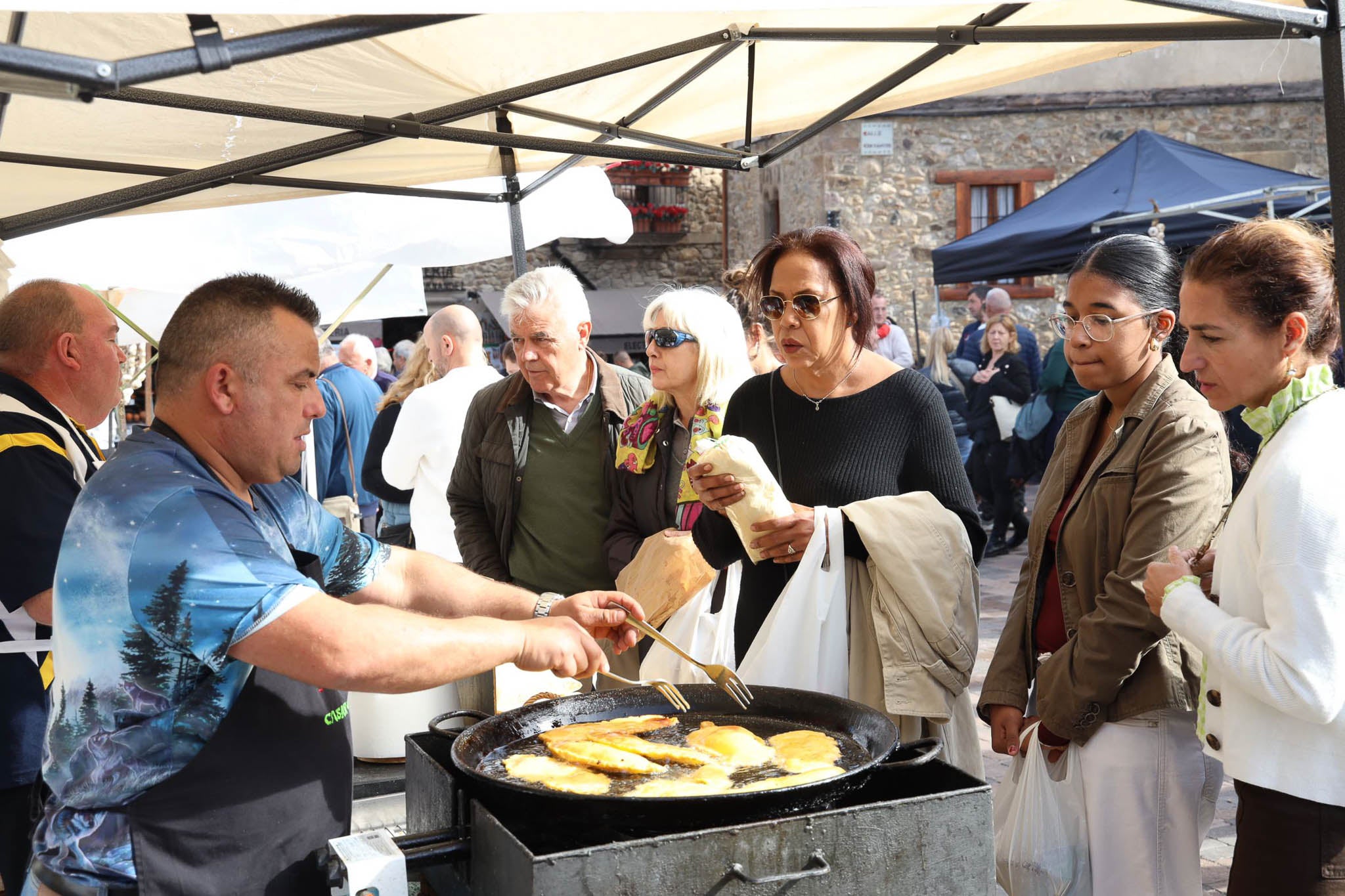 Un tendero frie su producto ante la mirada de los visitantes. 