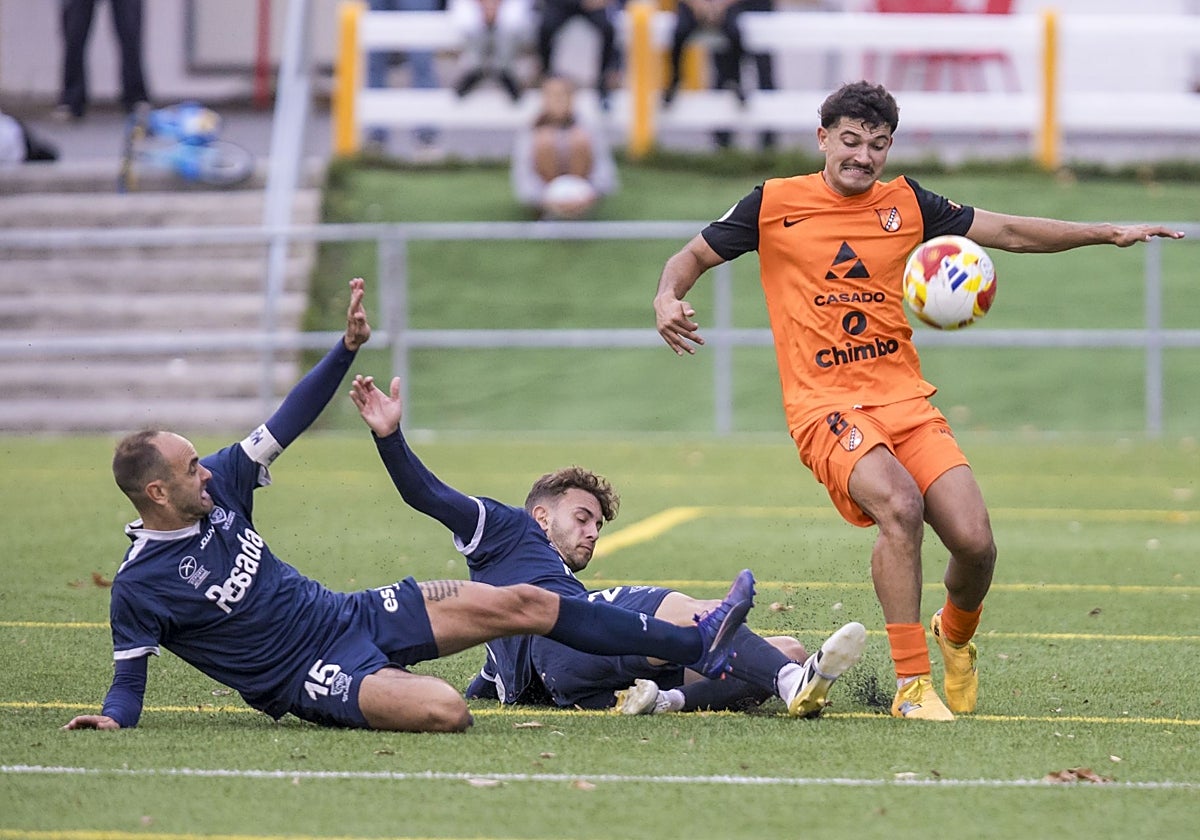 Abad, del Sámano, trata de controlar el balón mientras dos rivales del Marino de Luanco intentan frenarlo