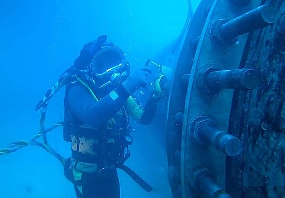 Un buzo profesional durante el proceso de instalación de una tubería subacuática.