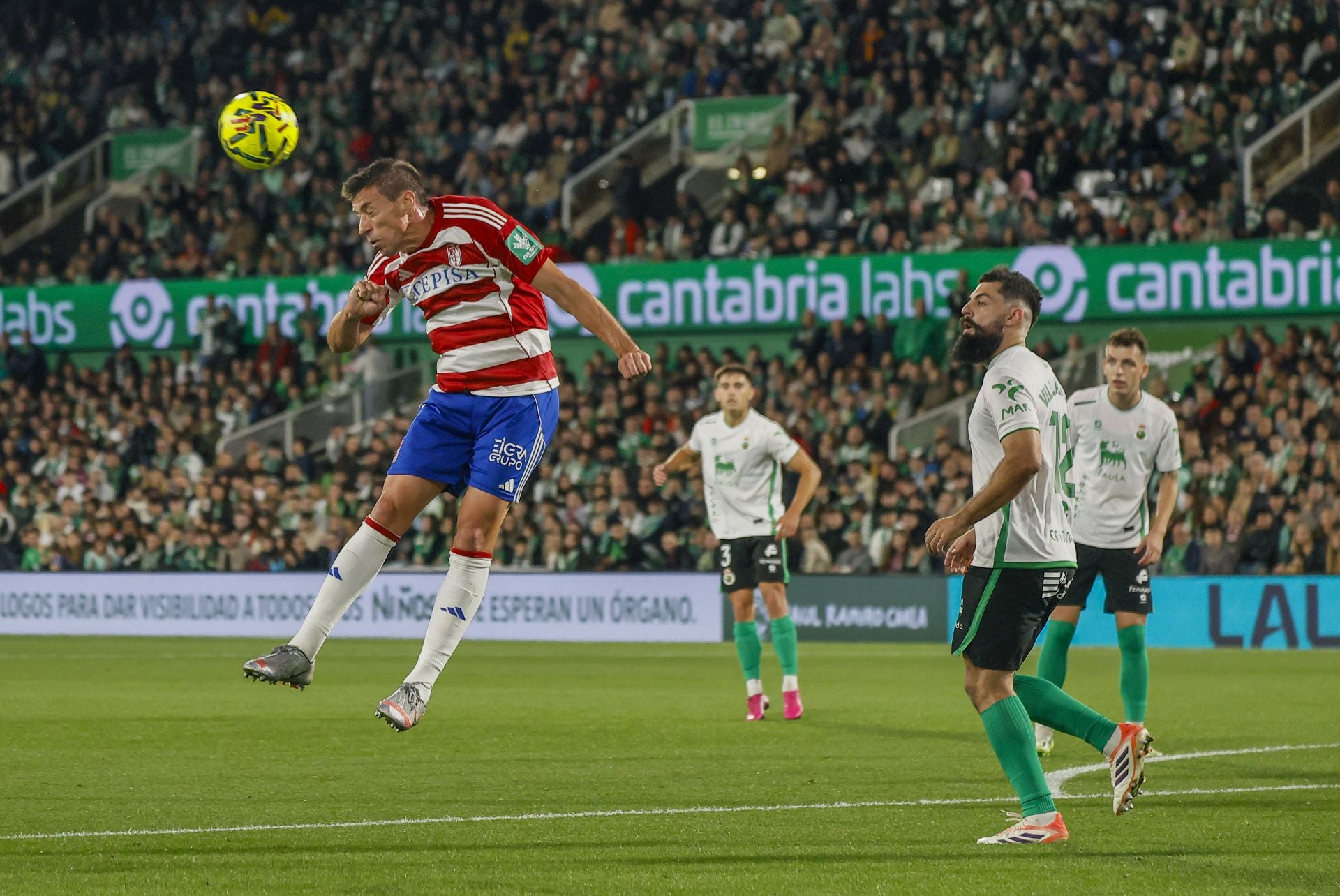 Un jugador del Granada cabecea el balón ante Villalibre