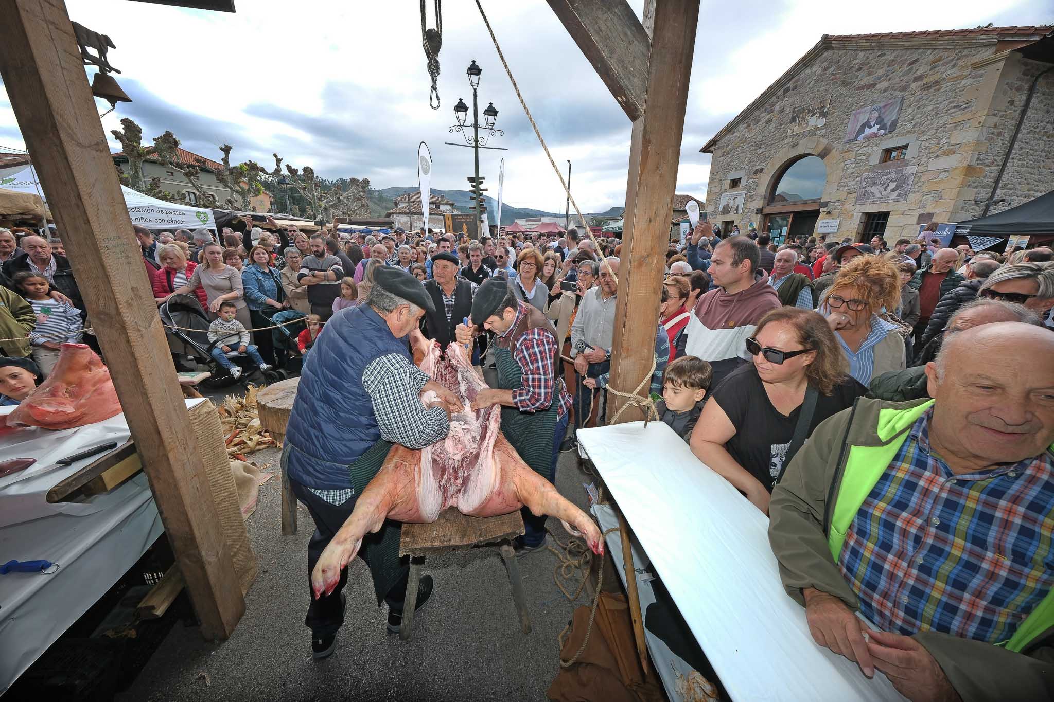 Dos hombres realizan la bajada del cerdo en medio de la plaza ante el público expectante.