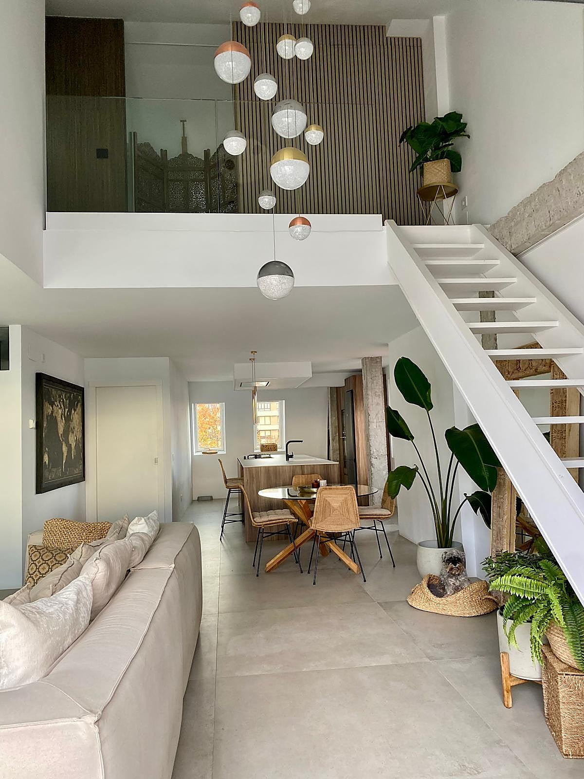 En Santander, este espacio diáfano y moderno destaca por la gran lámpara colgante, la escalera ligera y la combinación de los tonos neutros con las plantas.