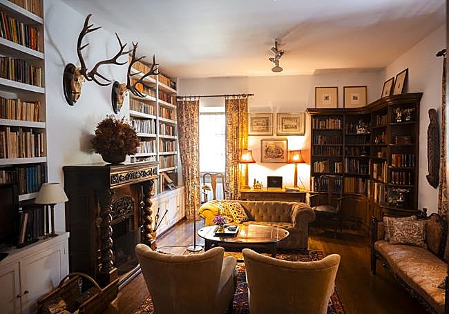 Salón-biblioteca. Una chimenea tallada preside esta estancia en la que los libros se integran como parte del mobiliario, creando un ambiente cálido y lleno de historia.