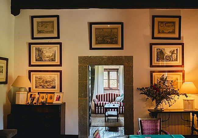 Entrada al salón principal. A través de un marco de piedra, flanqueado por grabados enmarcados y colocados de forma simétrica, se adivina un acogedor rincón con sofá a rayas.