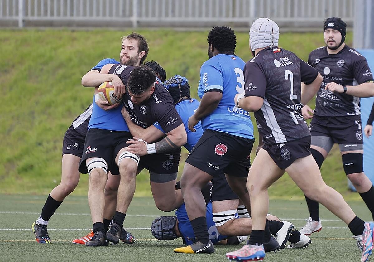 Un jugador intentando ganar metros con el balón mientras el rival trata de placarlo.