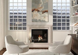 El salón está presidido por una chimenea, dos butacas tapizadas en bouclé, una gran alfombra y una reproducción de 'La creación de Adán', de Miguel Ángel.