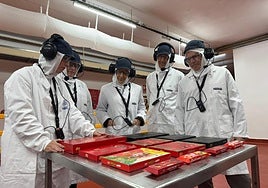 La presidenta de Cantabria, María José Sáenz de Buruaga, en el centro de la imagen, atiende las explicaciones de un empleado durante su recorrido por la fábrica.