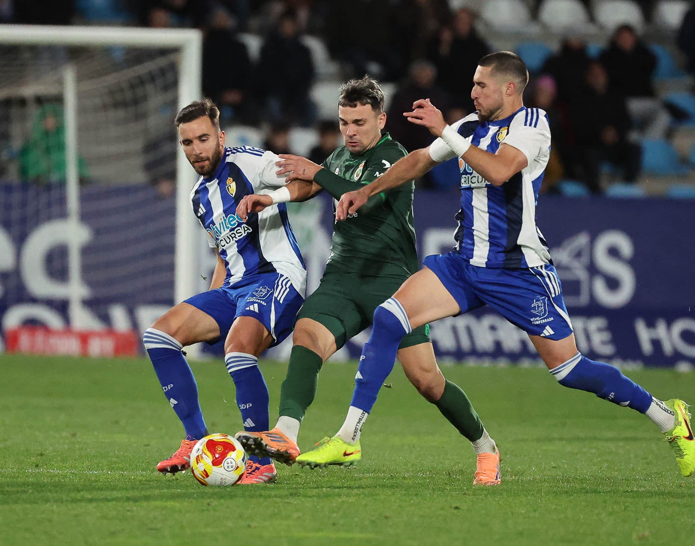 Juan Carlos Arana pugna por la pelota entre dos rivales.