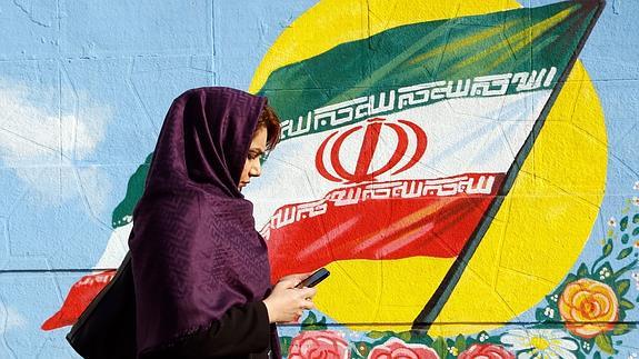 Una mujer iraní consulta su móvil en una calle de Teherán.