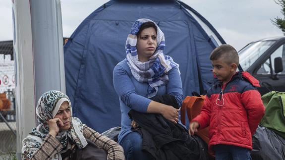 Varios refugiados esperan junto a sus pertenenecias en el campo improvisado de la localidad de Polykastro. 