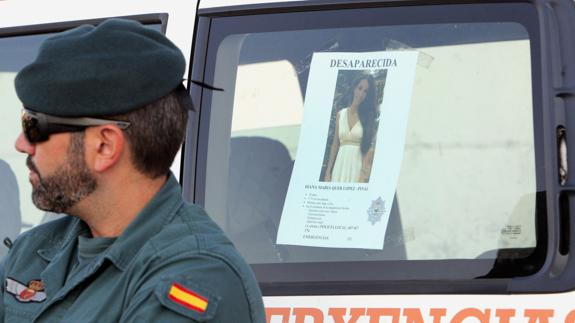 Un efectivo de la Guardia Civil junto al cartel de Diana Quer. 
