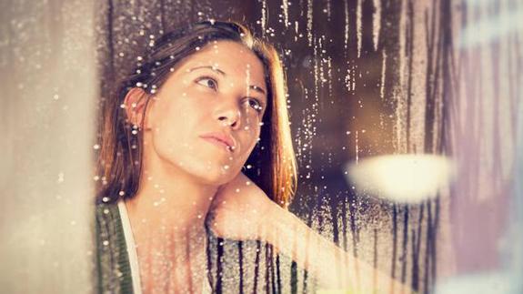 Una mujer, mirando la lluvia.