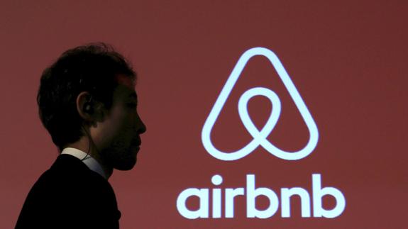 Un hombre pasa ante el logo de la plataforma Airbnb.