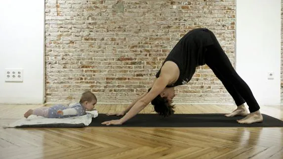 Una mamá realiza una asana con su bebé. 