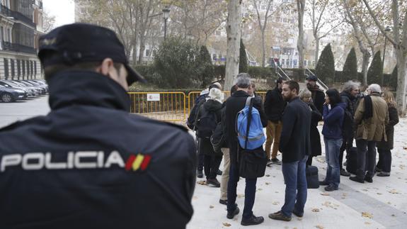 Varios miembros de la CUP, vigilados por un policía.