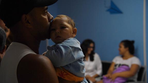 Una mujer sostiene a su hija enferma de Zika en Brasil. 