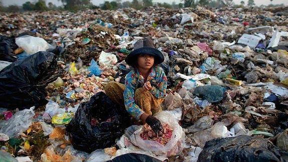 Una menor busca alimento para los cerdos entre la basura de Anlong Pi.