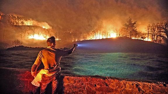 Un hombre al que se abraza una niña contempla el fuego en Barcenilla