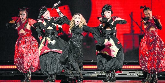 Madonna, durante el concierto en el Taipei Arena. Arriba, el momento en el que se envolvió con la bandera de Taiwán.