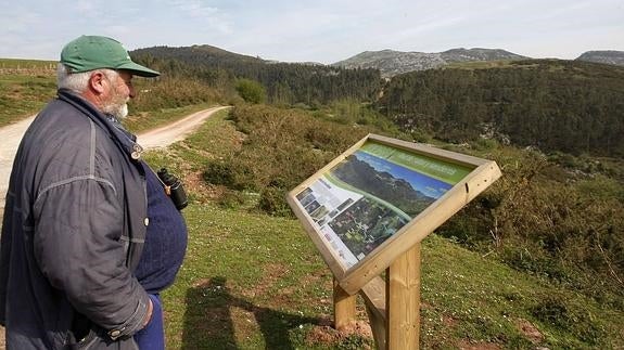 Un vecino mira uno de los carteles informativos en el Monte Dobra. 