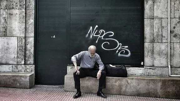 Un jubilado con gesto apesadumbrado descansa en una calle del centro de Atenas