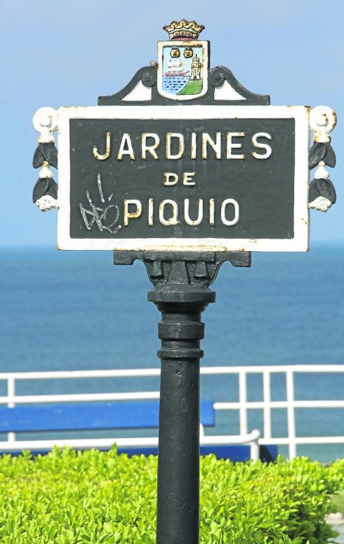 Placa histórica sobre mástil en los jardines junto al mar.