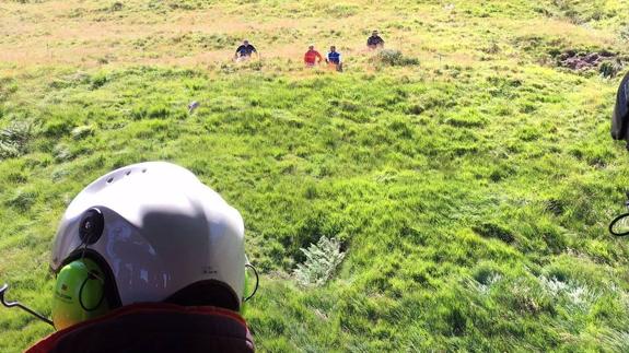 Uno de los rescatadores mira desde el helicoptero el lugar donde se encuentra el herido.