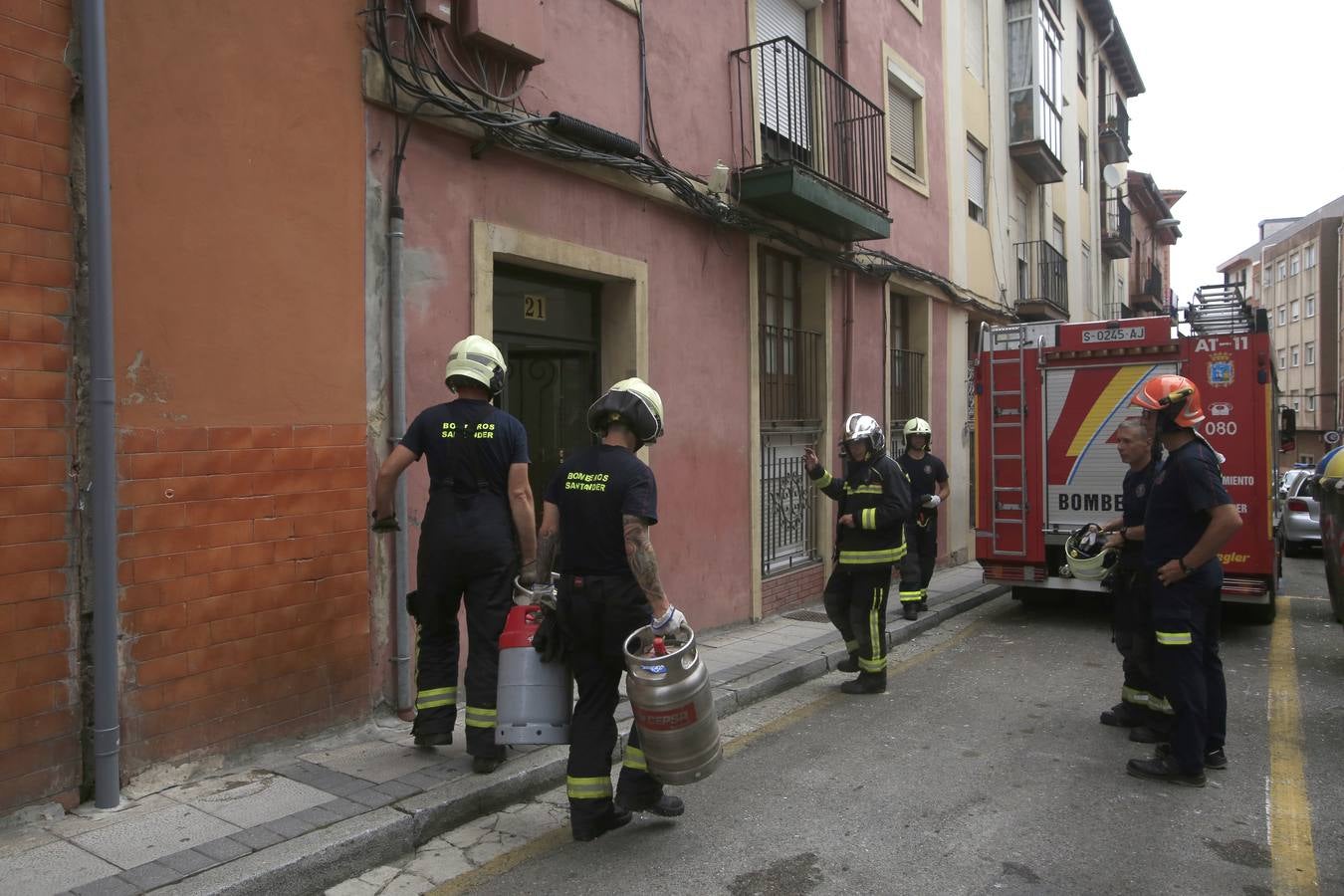 Varios bomberos cargan con las bombonas de butano que había en el edificio.