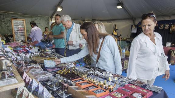 Visitantes de la feria observan objetos en uno de los puestos.