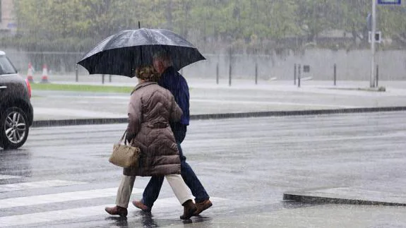 Dos personas caminan bajo la lluvia en Santander.