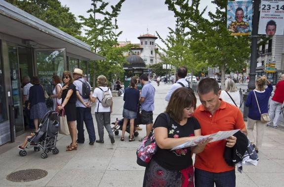 Una pareja mira un mapa de Santander mientras otro grupo hace cola para entrar en la oficina de turismo.
