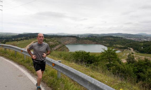 Un corredor pasa junto a los terrenos de la antigua mina de Reocín, que se inundó tras su cierre en 2003. 