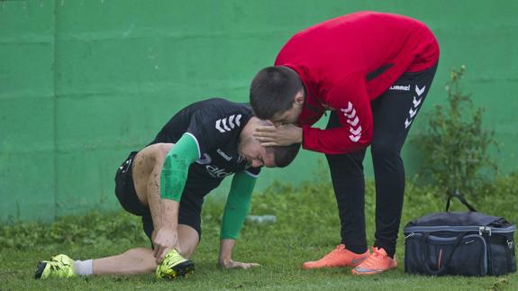 Héber, tendido sobre el césped, recibe la atención del fisioterapeuta del equipo Fran Rincón, tras lesionarse en el tobillo durante la sesión matutina de ayer.