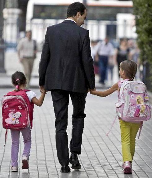 Un padre lleva a sus hijas al colegio.