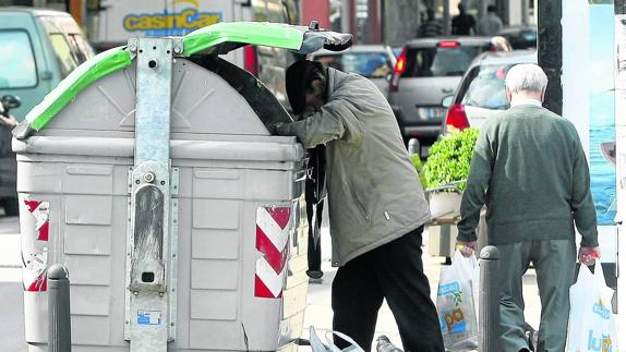 Un ciudadano busca comida en un contenedor de basura de Torrelavega. 