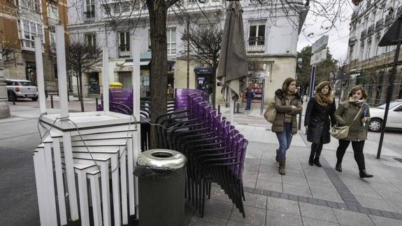 Mesas y sillas amontonadas en la calle y amarradas a un árbol, en la calle de Hernán Cortés, en la jornada de ayer.