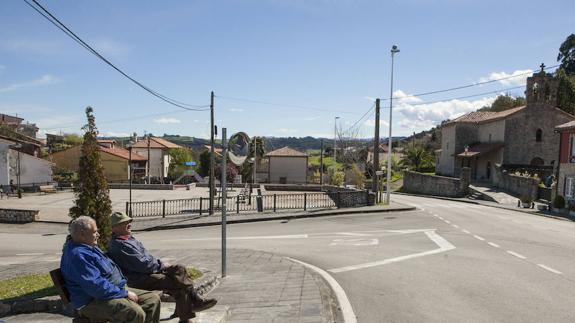 Dos vecinos de La Acebosa descansan en uno de los bancos de la plaza, junto a la bolera