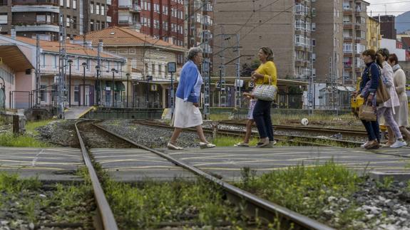 Varias personas atraviesan el paso a nivel de la calle Pablo Garnica, uno de los que hay en la ciudad y que divide en dos a Torrelavega. 