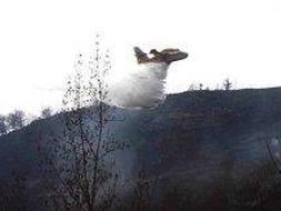 Un hidroavión arroja agua para sofocar el incendio desatado en Cossío, en la zona del Nansa, uno de los más virulentos. ::                             SANE