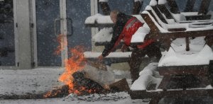 Un operario arroja objetos a una hoguera en las inmediaciones de Brañavieja, que ayer amaneció cubierta de una capa de nieve. ::                             SANE