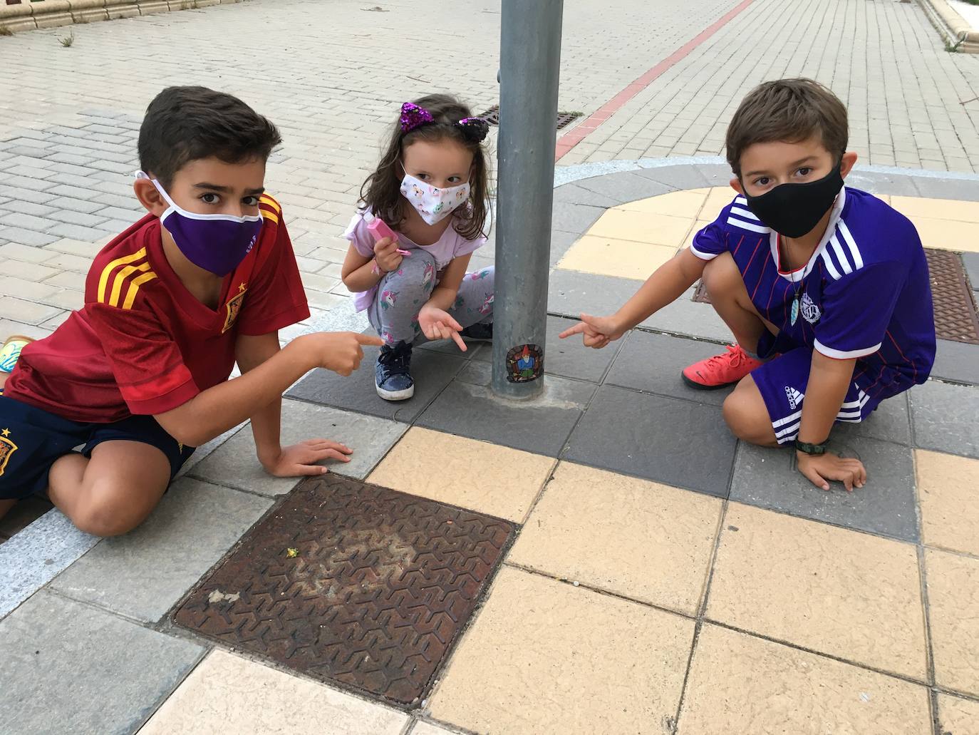 Tres niños señalan uno de los gnomos nada más localizarlo en la base de una farola de un parque de Arroyo de la Encomienda. 