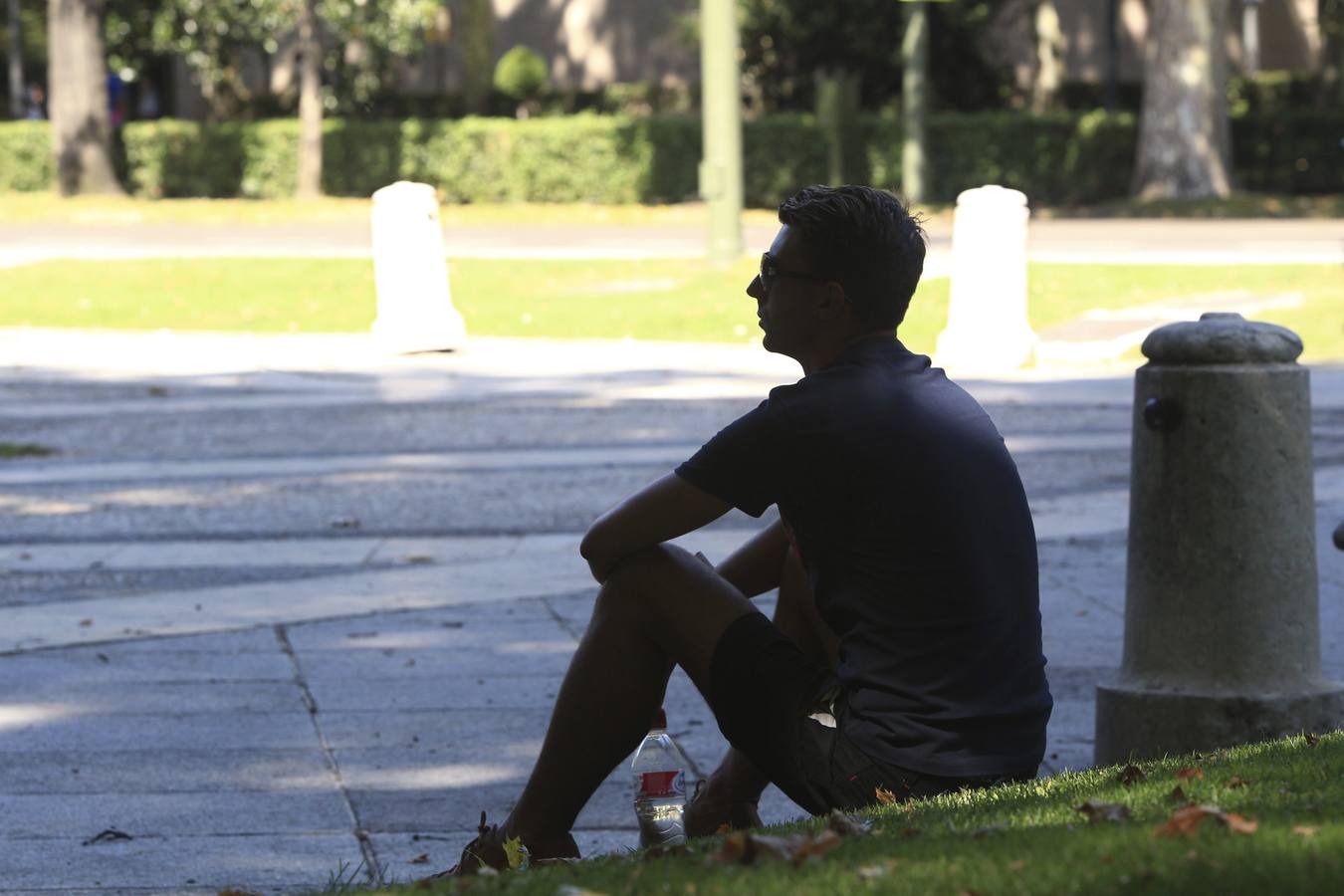 Un hombre descansa en la sombra frente al Paseo de la Castellana en Madrid, en una jornada con temperaturas de hasta 38 grados en plena ola de calor.